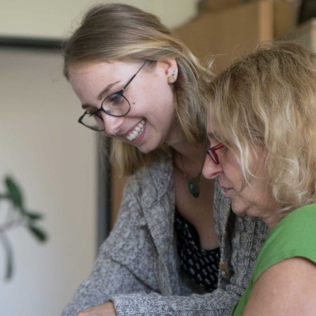 Eine junge Frau erklärt einer älteren Dame etwas.
