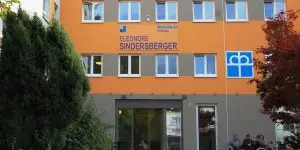 Ein oranges Gebäude, über dem Eingangsbereich steht Eleonore Sindersberger