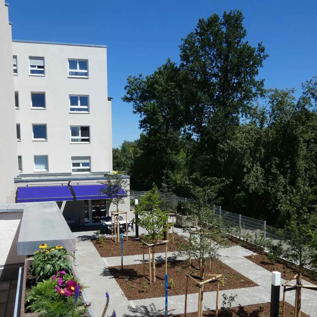 Ein modernes Gebäude von hinten, davor ein frisch angelegter Park