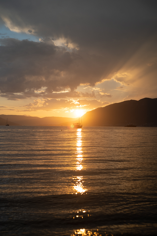 Ein Boot auf einem See, dahinter geht die Sonne unter.