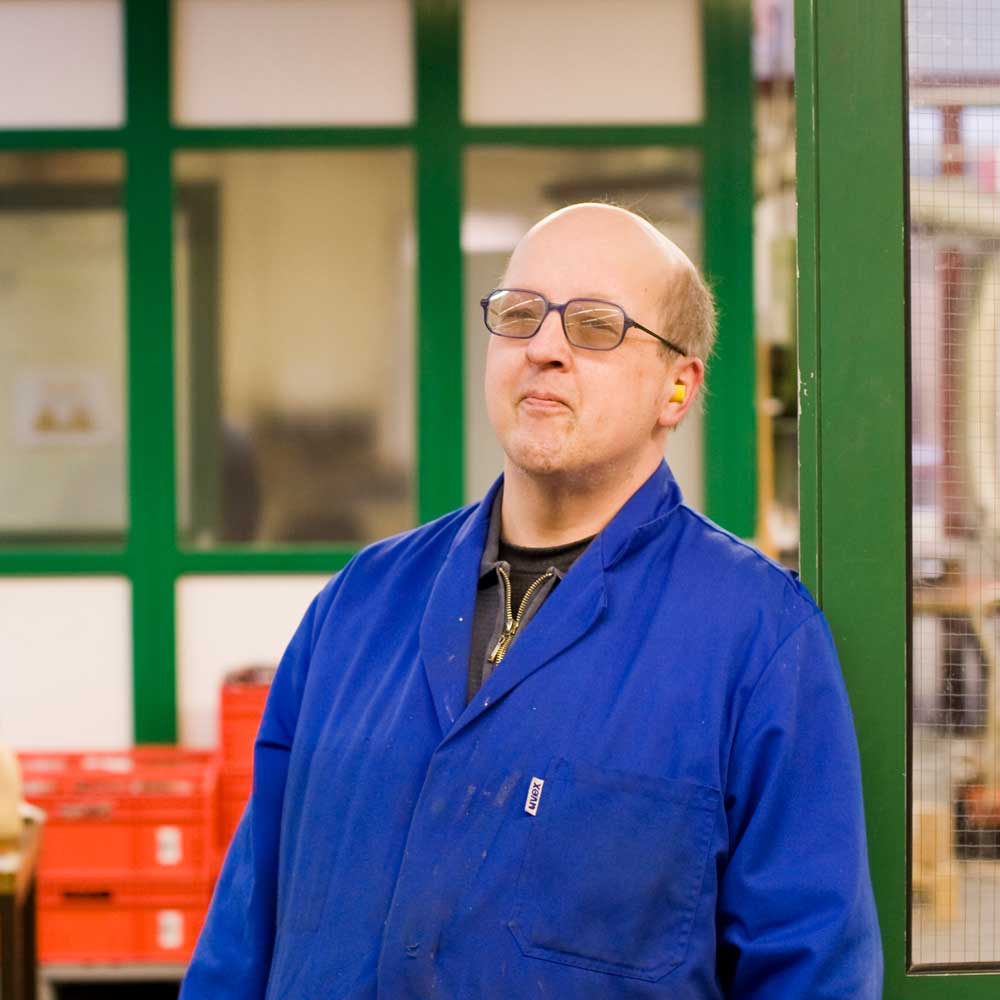 Ein Mann in einer Werkstatt in einem Blaumann