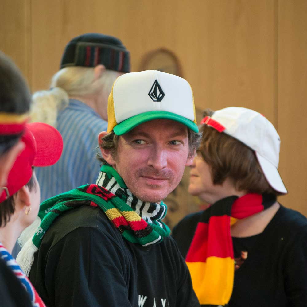 Drei Fussballfans in einem Raum mit anderen Menschen