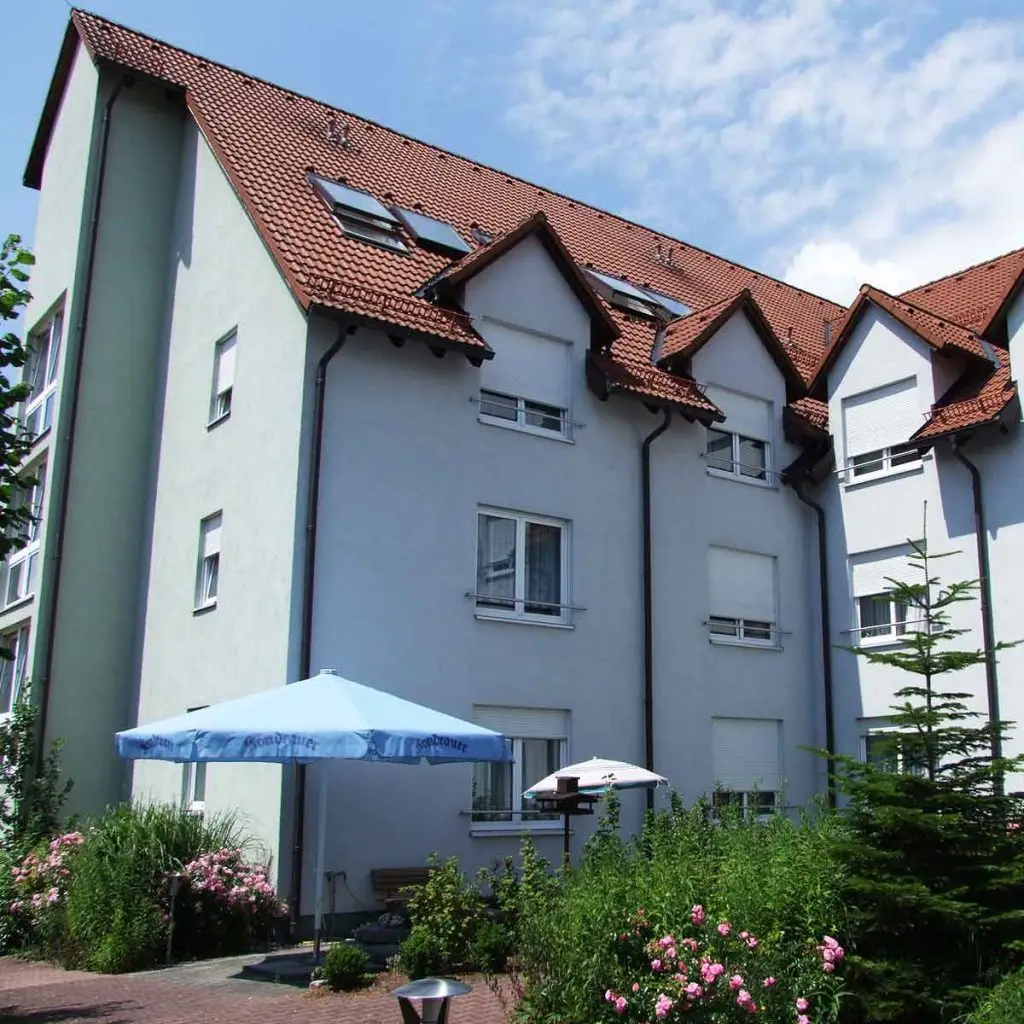 Das Gebäude von aussen, davor ein blauer Sonnenschirm