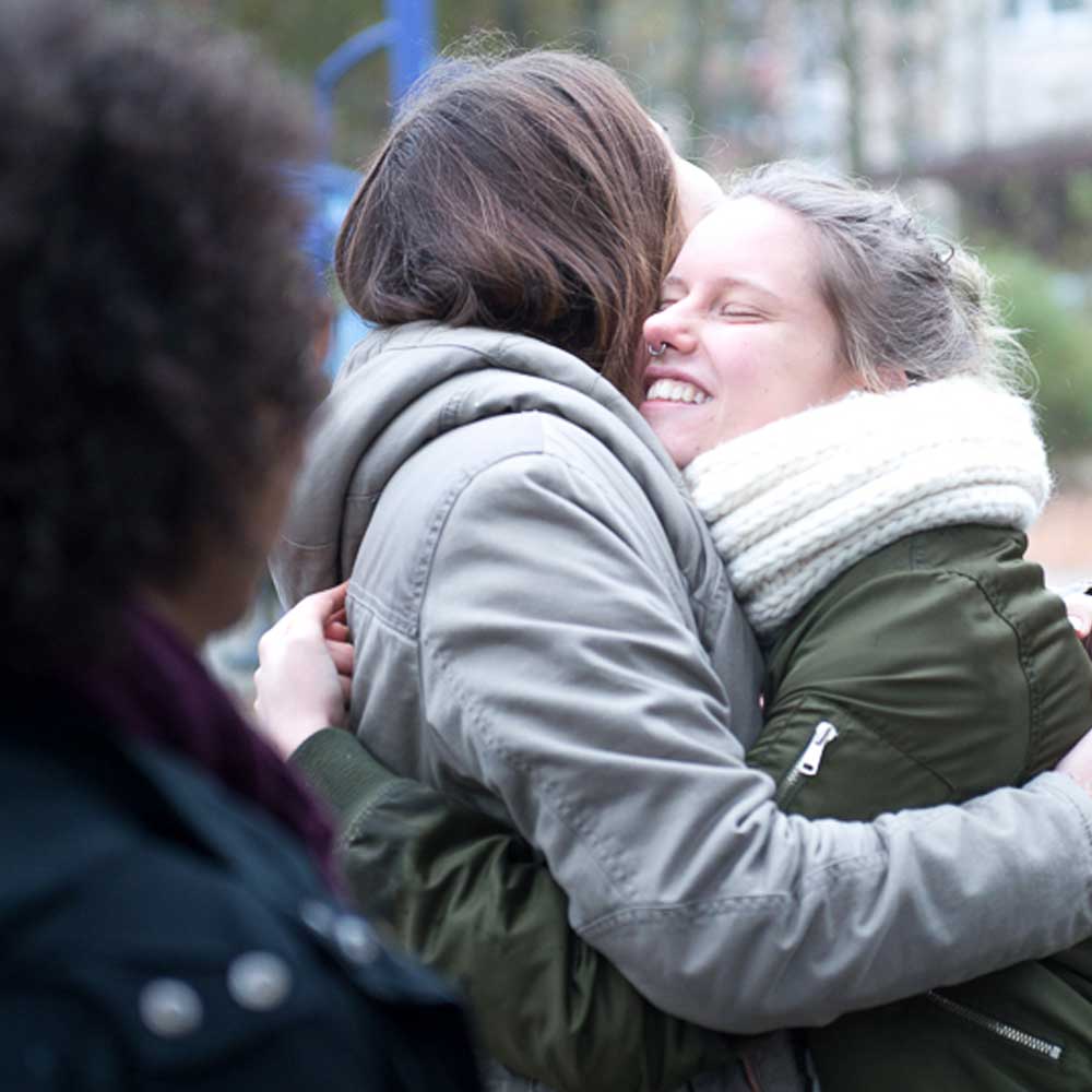 Zwei junge Mädchen umarmen sich auf einem Spielplatz.