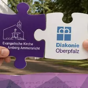 Zwei Puzzle-Steine, die die Zusammenarbeit von Kirche und Diakonie symbolisieren.